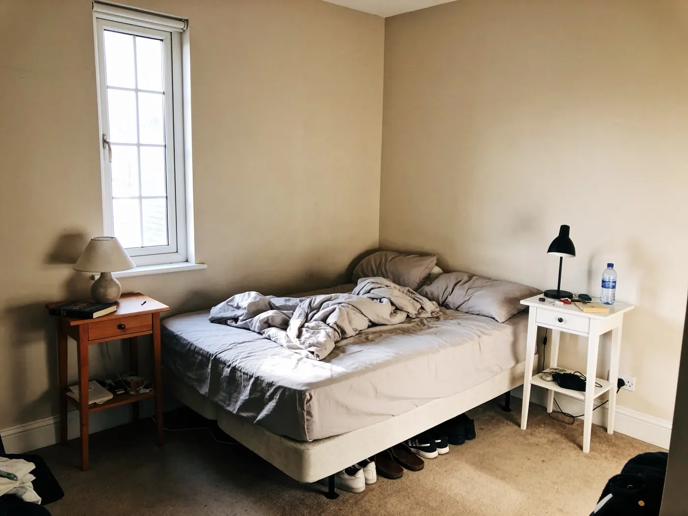 The same bedroom before: an unmade bed and bare walls